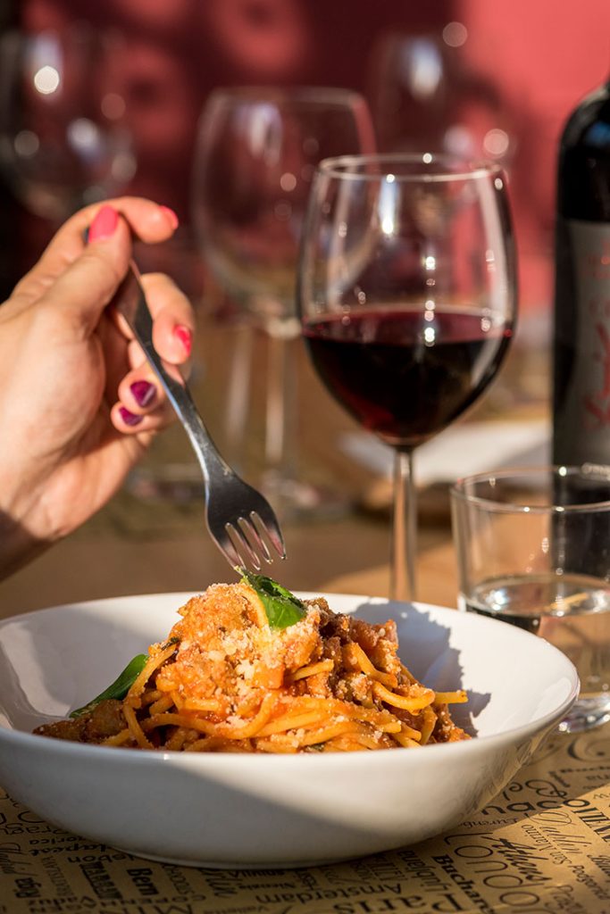 ristorante aperto per pranzo rivarolo mangiando pasta con un bicchiere di vino rosso